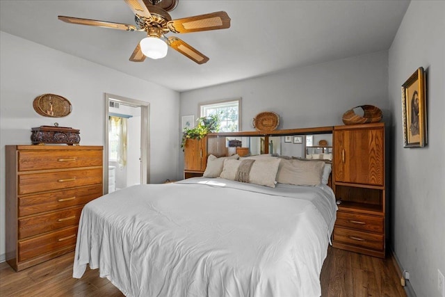 bedroom with ceiling fan, dark wood-type flooring, and connected bathroom