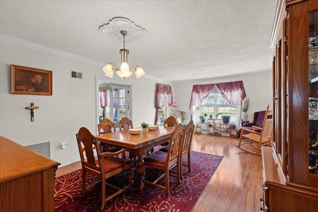 dining room with a textured ceiling, crown molding, a chandelier, and dark hardwood / wood-style floors