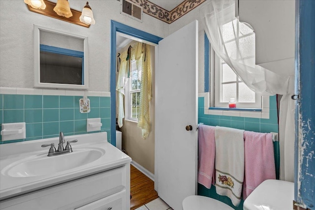 bathroom with vanity, hardwood / wood-style flooring, toilet, and tile walls