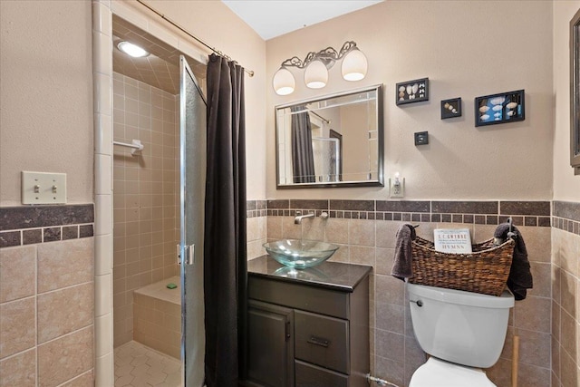 bathroom with walk in shower, vanity, toilet, and tile walls