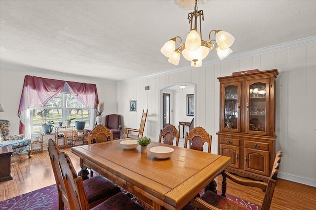 dining room featuring crown molding, dark wood-type flooring, a textured ceiling, and a notable chandelier