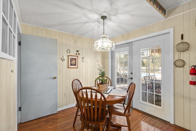 dining space with hardwood / wood-style floors, french doors, and wooden walls