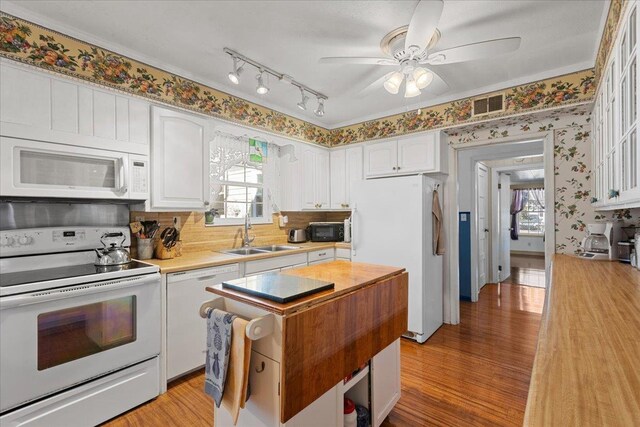 kitchen featuring sink, light hardwood / wood-style flooring, crown molding, white appliances, and white cabinets