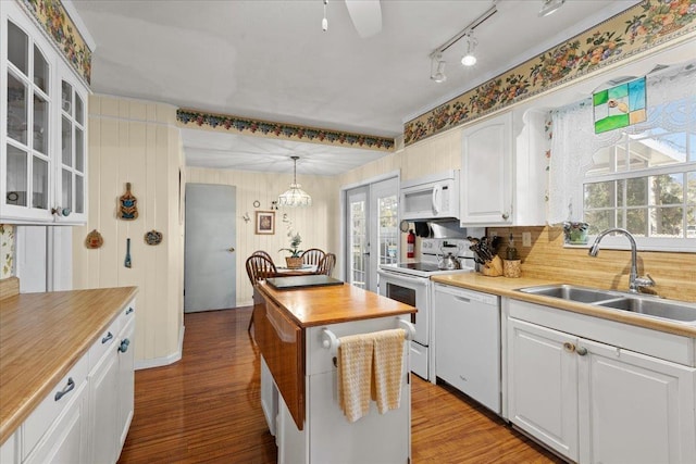 kitchen featuring white appliances, sink, light hardwood / wood-style flooring, white cabinets, and hanging light fixtures