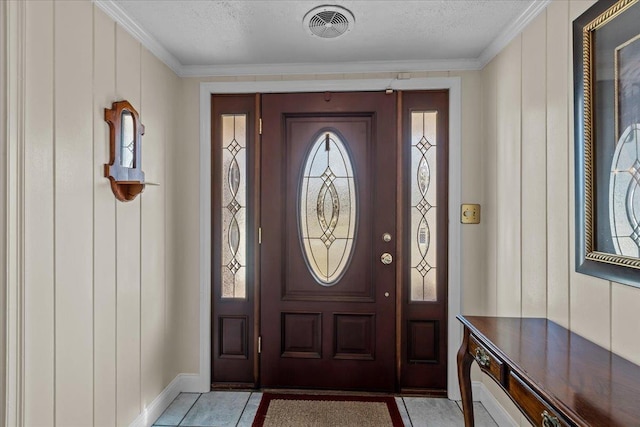 foyer featuring crown molding, light tile patterned floors, and a textured ceiling