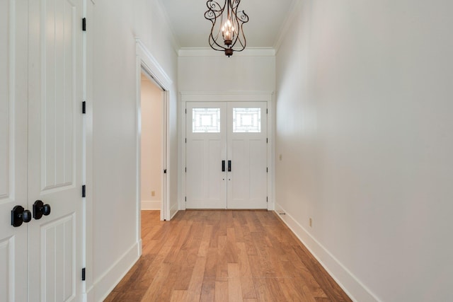 doorway featuring light wood-type flooring, baseboards, ornamental molding, and a chandelier