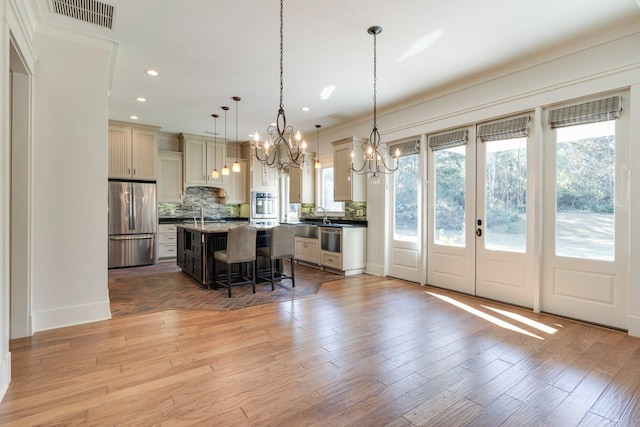 kitchen featuring a breakfast bar, light wood finished floors, tasteful backsplash, visible vents, and appliances with stainless steel finishes