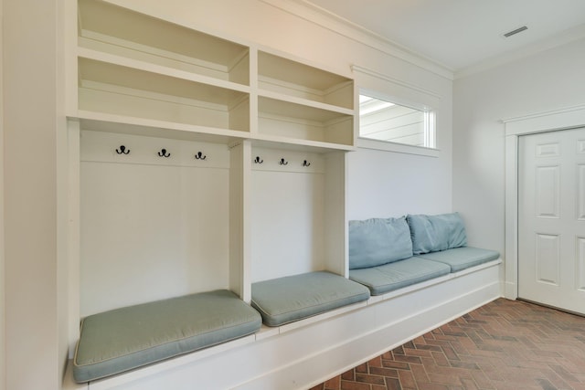 mudroom featuring ornamental molding, brick floor, and visible vents