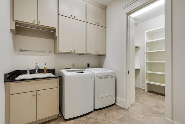 washroom featuring washing machine and dryer, cabinet space, a sink, and light tile patterned floors