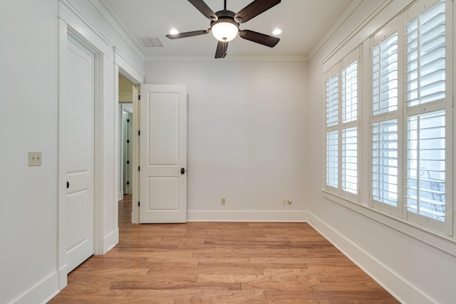 empty room with light wood-style floors, plenty of natural light, and crown molding