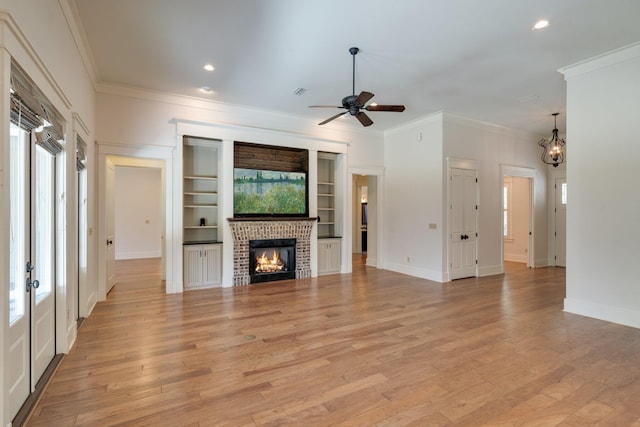 unfurnished living room with light wood-type flooring, plenty of natural light, a fireplace, and ornamental molding