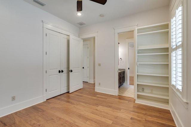 unfurnished bedroom with a closet, visible vents, light wood-style flooring, and baseboards