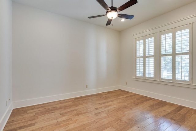 empty room featuring light wood finished floors, baseboards, and a ceiling fan