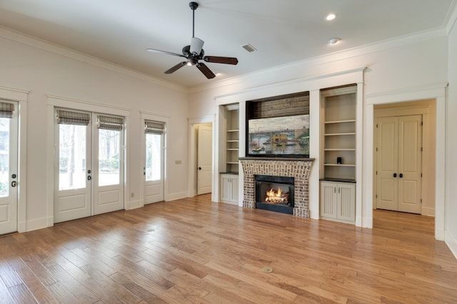 unfurnished living room with crown molding, visible vents, light wood-style flooring, a brick fireplace, and baseboards