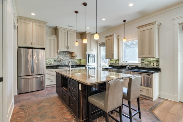 kitchen featuring appliances with stainless steel finishes, cream cabinetry, a sink, and a warming drawer