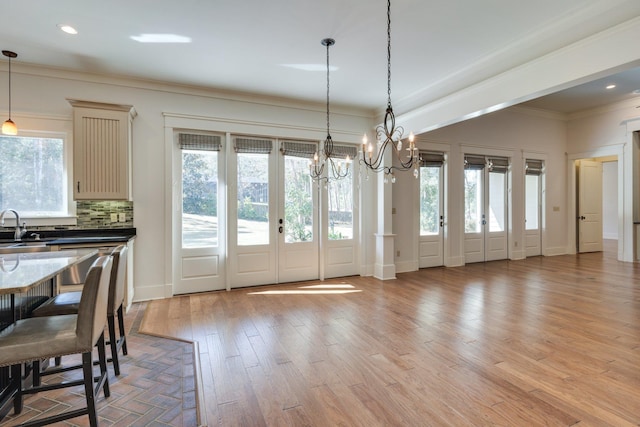 dining space with baseboards, ornamental molding, light wood-style floors, a notable chandelier, and recessed lighting