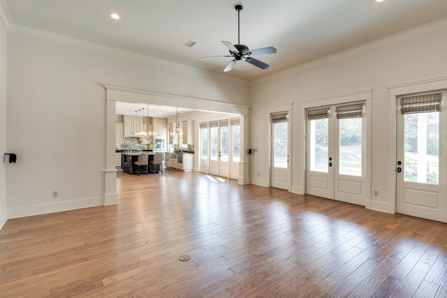 unfurnished living room with light wood finished floors, plenty of natural light, and crown molding