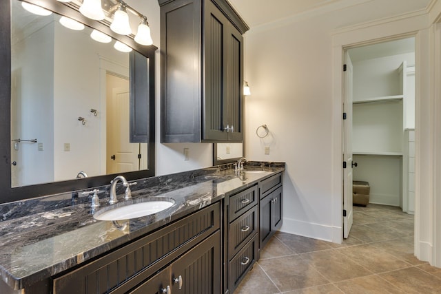 bathroom featuring double vanity, baseboards, a sink, and tile patterned floors