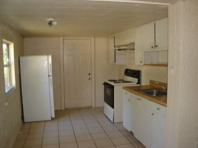 kitchen with white cabinetry, white appliances, sink, and light tile patterned floors