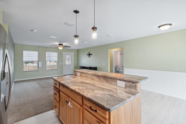 kitchen with light stone counters, ceiling fan, stainless steel fridge, pendant lighting, and light colored carpet