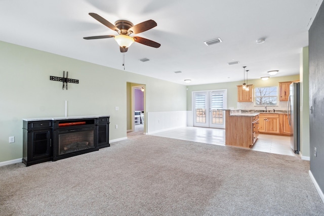 unfurnished living room with sink, light colored carpet, and ceiling fan