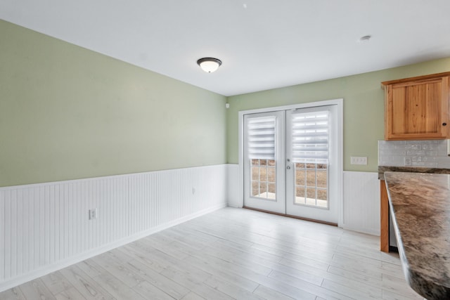 unfurnished dining area with french doors and light wood-type flooring