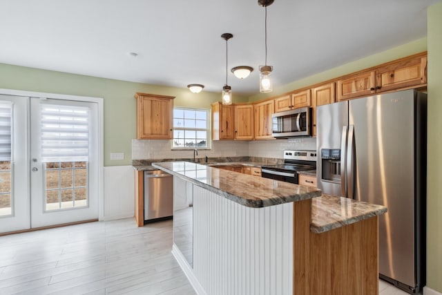 kitchen with stainless steel appliances, a center island, stone countertops, decorative light fixtures, and light wood-type flooring