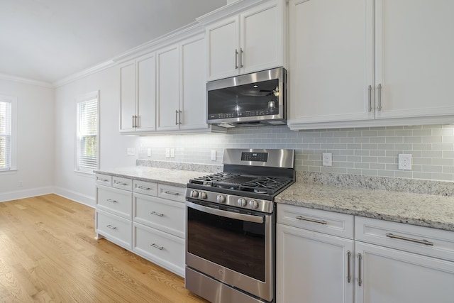 kitchen with white cabinetry, crown molding, tasteful backsplash, light wood-type flooring, and appliances with stainless steel finishes