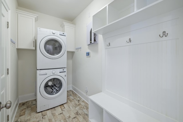 laundry area featuring light hardwood / wood-style floors, cabinets, and stacked washer / dryer