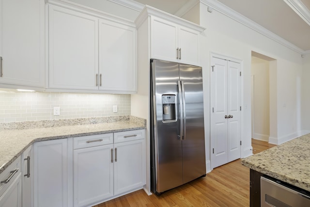 kitchen with light stone counters, light wood-type flooring, stainless steel fridge, decorative backsplash, and white cabinets