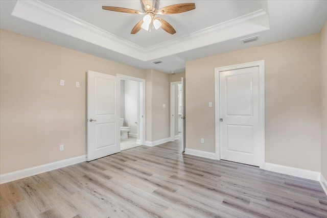 unfurnished bedroom with ornamental molding, a raised ceiling, and light hardwood / wood-style flooring