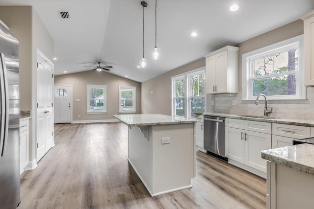 kitchen featuring a kitchen island, appliances with stainless steel finishes, pendant lighting, white cabinetry, and sink