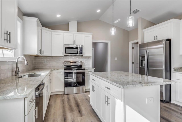 kitchen with sink, decorative light fixtures, a kitchen island, stainless steel appliances, and white cabinets