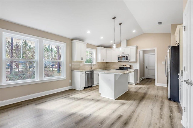 kitchen featuring appliances with stainless steel finishes, white cabinetry, sink, hanging light fixtures, and a center island