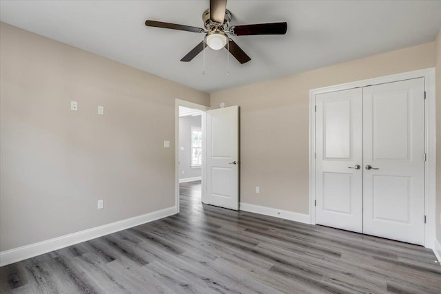 unfurnished bedroom with ceiling fan, wood-type flooring, and a closet