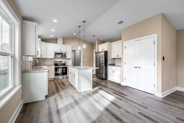 kitchen with a kitchen island, appliances with stainless steel finishes, white cabinetry, sink, and hanging light fixtures