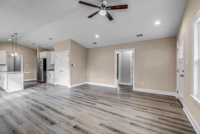 unfurnished living room with ceiling fan, lofted ceiling, and light wood-type flooring