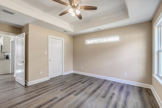 unfurnished bedroom featuring crown molding, a raised ceiling, ceiling fan, and light wood-type flooring