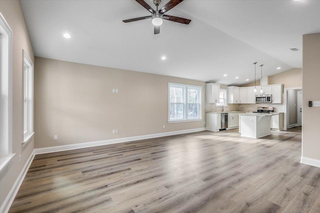 unfurnished living room with vaulted ceiling, sink, ceiling fan, and light hardwood / wood-style flooring