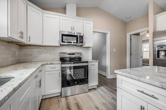 kitchen with white cabinetry, stainless steel appliances, and light stone counters