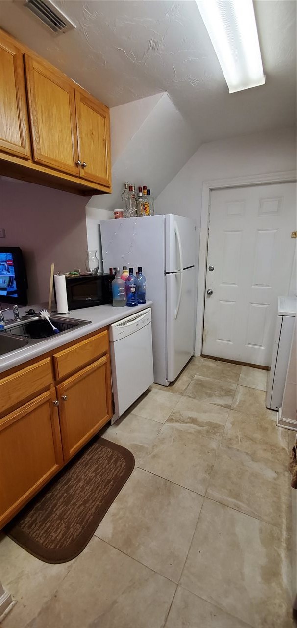 kitchen with washer / clothes dryer, dishwasher, lofted ceiling, and sink