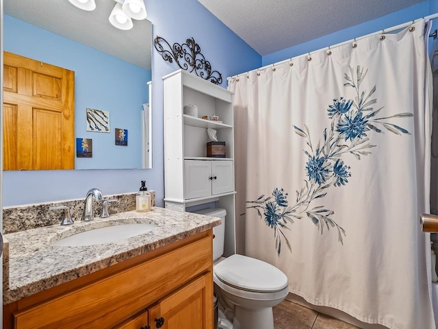 bathroom featuring tile patterned floors, vanity, toilet, and a textured ceiling