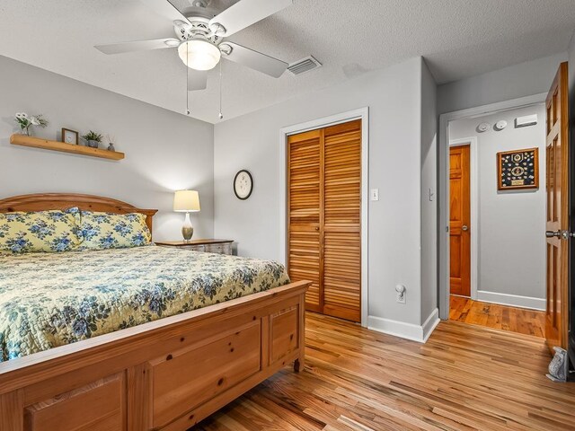 bedroom featuring ceiling fan, a closet, light hardwood / wood-style floors, and a textured ceiling