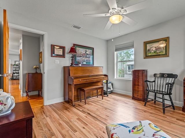 living area with ceiling fan and light hardwood / wood-style floors