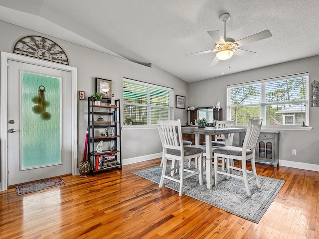 dining space with hardwood / wood-style flooring, vaulted ceiling, a wealth of natural light, and ceiling fan