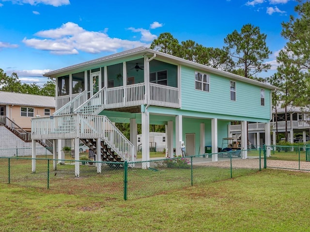 rear view of property featuring a sunroom, a yard, and ceiling fan