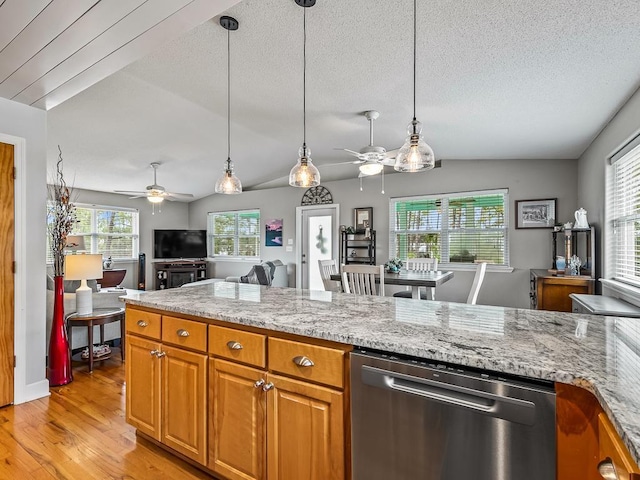 kitchen featuring a healthy amount of sunlight, light stone counters, stainless steel dishwasher, and lofted ceiling