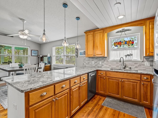 kitchen featuring dishwasher, kitchen peninsula, sink, and hanging light fixtures