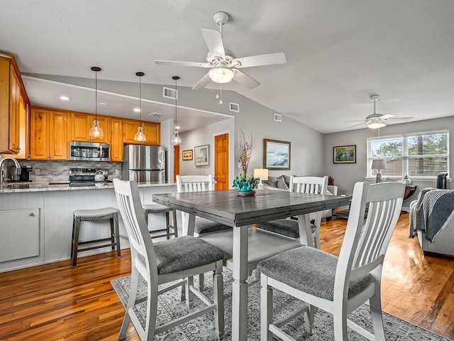 dining space with ceiling fan, light wood-type flooring, lofted ceiling, and sink