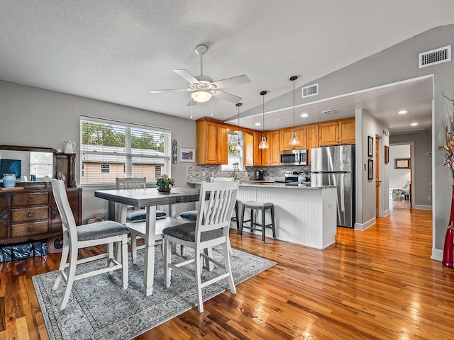 dining room featuring light wood-type flooring, ceiling fan, and lofted ceiling